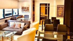 Una sala de estar moderna con sofá, mesa de centro y comedor con sillas.