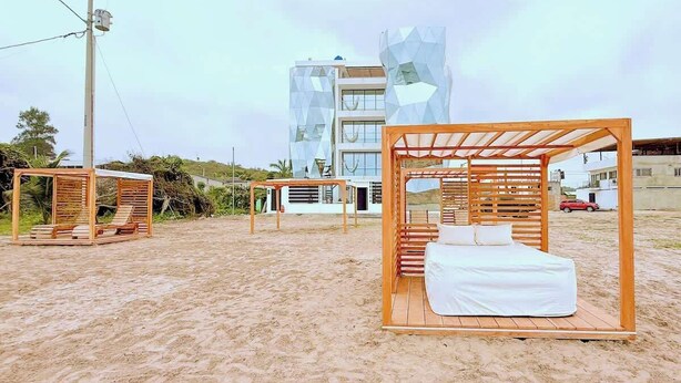 Une plage agrémentée de structures en bois, notamment un lit et un espace de détente.