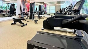 Une salle de sport équipée de tapis de course, d’appareils de musculation et d’un mur recouvert de miroirs.