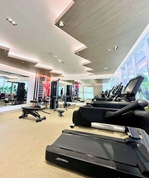 Un gimnasio con cintas de correr, máquinas de pesas y un espejo grande.