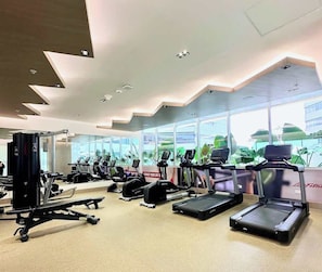 Ein Fitnessstudio mit Laufbändern, Kraftgeräten und Trainingsmatten.