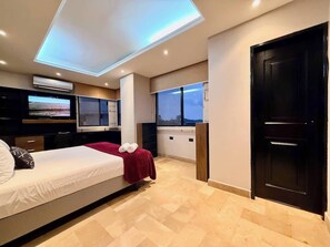 A modern bedroom with a bed, TV, and a view of the city. - Large Apt in Lomas Urdesa • Sleeps 8 • BBQ (Guayaquil)