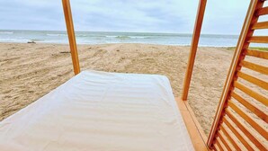 A beach hut with a bed, wooden slats, and a view of the ocean. - Beachfront, pool, whirlpool & firepit (Montanita)