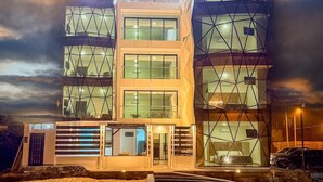 A multi-story hotel with a modern geometric facade, large windows, and a well-lit entrance.