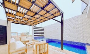 A covered outdoor area with a pool, seating, and a view of the beach.