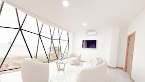 A modern room with a large window, white furniture, and a flat-screen TV. - Oceanfront Paradise with Pool, Hot Tub and Firepit (Montanita)