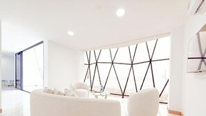 A modern living room with a white sofa, a coffee table, and a geometric wall design. - Oceanfront Paradise with Pool, Hot Tub and Firepit (Montanita)