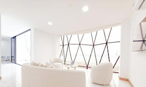 Un salon moderne avec un canapé blanc, une table basse et un motif géométrique sur le mur.