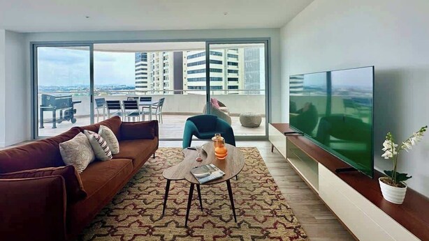A modern living room with a sofa, coffee table, and TV. - Luxurious Escape at Santana lofts includes Parking (Guayaquil)