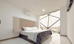 A modern bedroom with a bed, a headboard, a window with a geometric view, and an air conditioning unit. - Beachfront, pool, whirlpool & firepit (Montanita)