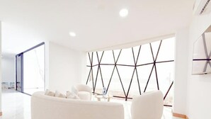 Un salon moderne avec un canapé blanc, une table basse et un motif géométrique sur le mur.