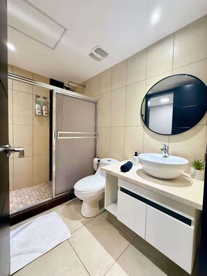 A modern bathroom with a toilet, sink, and shower. - Stylish 2BD Condo with River View (Guayaquil)