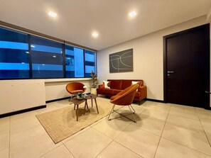 A modern living room with a sofa, two armchairs, a coffee table, and a rug. - Stylish 2BD Condo with River View (Guayaquil)