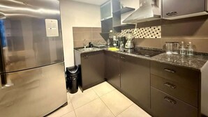 Una cucina moderna con elettrodomestici in acciaio inossidabile, una parete di fondo rivestita di piastrelle e mobili in legno scuro.