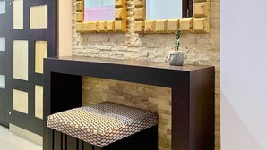 A modern interior with a wooden wall, a large mirror, a dark console table, and a patterned ottoman. - Poolside Condo w/Parking Near US Consulate (Guayaquil)