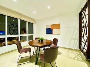A modern dining area with a round table, four chairs, and a potted plant. - Amazing 2BD apt near US Consulate includes Parking (Guayaquil)