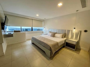 A modern bedroom with a bed, bedside tables, a TV, and a window. - Luxury Apartment on the 16th floor free Parking (Guayaquil)