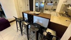 Eine kompakte Küche mit Kochinsel, Barhocker, Kühlschrank und Mikrowelle.