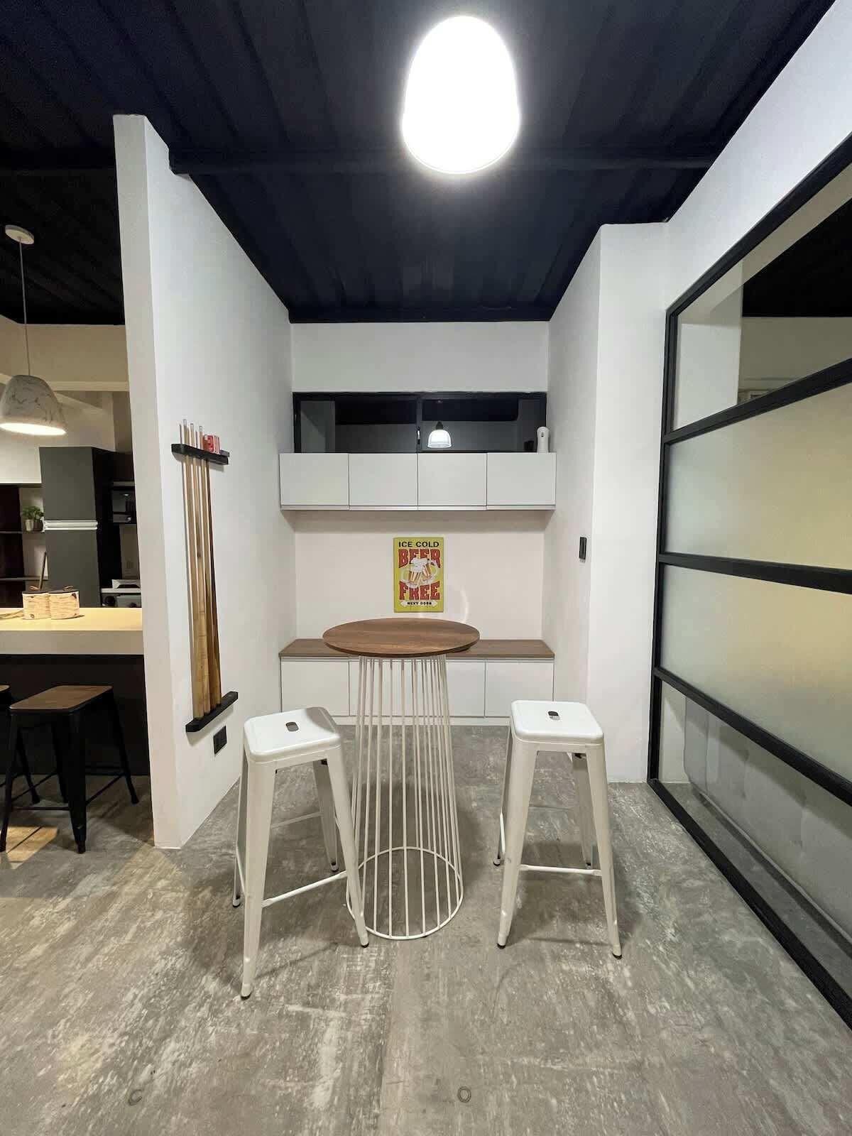 Une cuisine moderne avec un coin repas, un luminaire au plafond et une étagère murale agrémentée d’une enseigne.