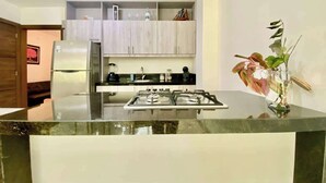 A modern kitchen with a central island, stainless steel appliances, and a potted plant.