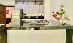 A modern kitchen with a central island, stainless steel appliances, and a potted plant.