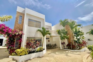 Un edificio moderno con un patio, mobiliario exterior y diversas plantas.