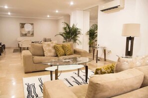 Un salon moderne avec un canapé beige, une table basse en verre et une lampe.