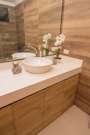 Une salle de bain avec un double lavabo, un miroir et un meuble-lavabo en bois.