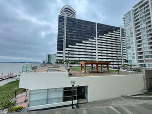Ein modernes Gebäude mit Dachterrasse, einer Holzpergola und Blick aufs Wasser.