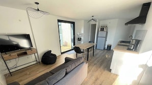 Een modern appartement met een zithoek, inclusief een bank, een televisie en een eettafel.