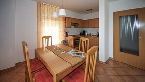 A compact kitchen with wooden cabinets, a tiled backsplash, and a dining table with chairs. - Gorgeous home in Röbel with lake view (Röbel)