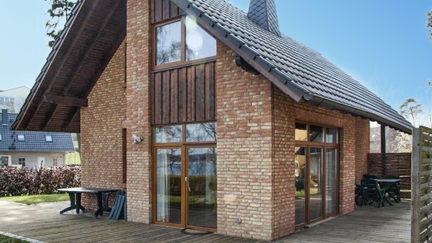A two-story brick house with large windows and a covered patio area. - Gorgeous home in Röbel with lake view (Röbel)