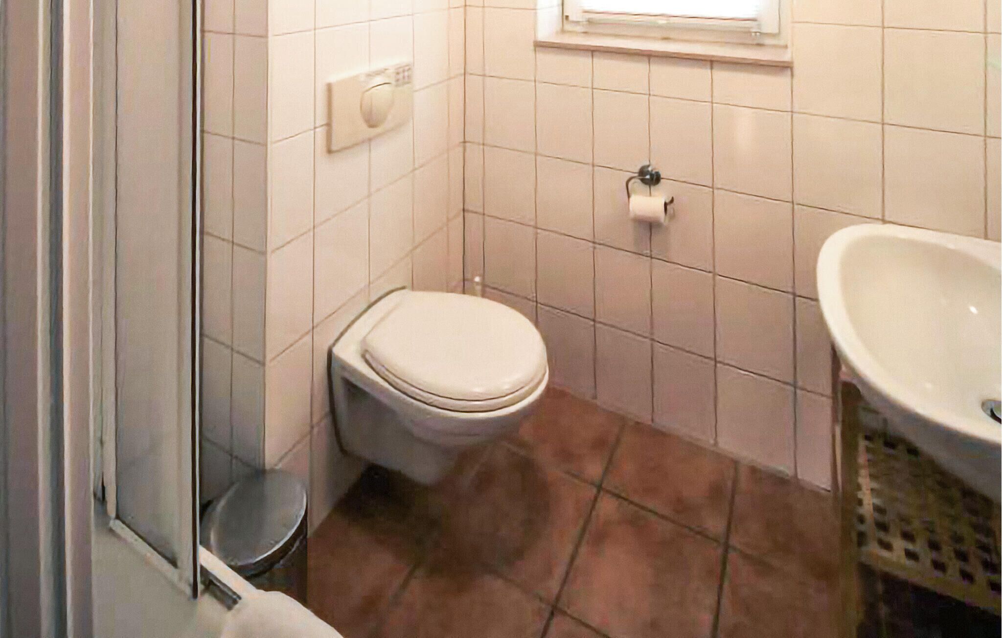 Une petite salle de bain avec des toilettes, un lavabo et une fenêtre.