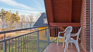 A balcony with a view of a grassy area and trees, a wooden ceiling, and a brick wall.