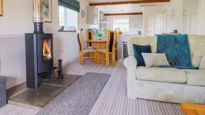 A cozy living room with a fireplace, a dining area, and a kitchen. - The Cottage Middle Westwater (Axminster)