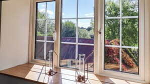 A room with a large sliding glass door leading to a balcony with a view of trees and a wooden deck. - The Cottage Middle Westwater (Axminster)