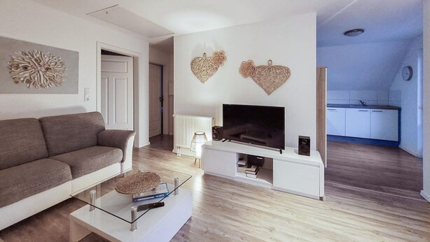 Ein stilvolles Wohnzimmer mit Sofa, Fernseher und Wandbildern.