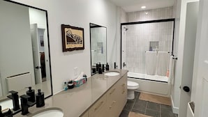 Een moderne badkamer met twee wastafels, een bad en een douche.