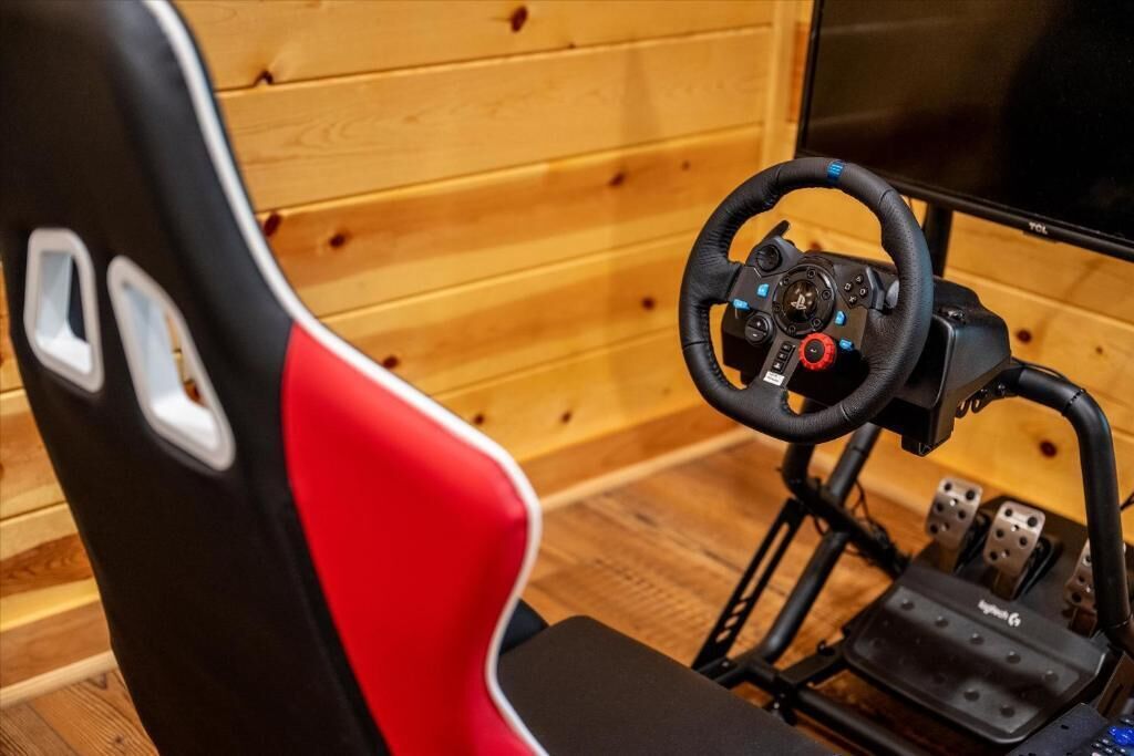 A racing simulator setup with a steering wheel, pedals, and a chair with a red and black design.