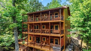 Une cabane en rondins à plusieurs étages, dotée de balcons et entourée d’une forêt dense.