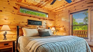 Une chambre dans une cabane en bois, avec un lit, des tables de chevet et une citation inspirante sur le mur.