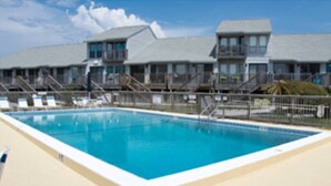 A swimming pool with a beige deck, surrounded by a fence and a row of buildings with balconies. - One - Too - Suite, Saint George Island, Beach Townhome (Eastpoint)