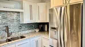 A kitchen with white cabinets, a stainless steel refrigerator, and a granite countertop. - Beautiful 2 bedroom, 2 bath Destin, Florida Condo! (Destin)