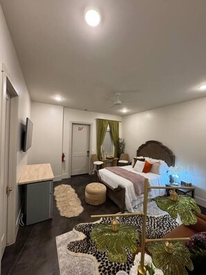 A bedroom with a bed, bedside table, lamp, and a small table with decorative items.