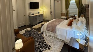 Et hotelværelse med en seng, et skrivebord, en stol, et fjernsyn og en dør med teksten 'EXIT'.