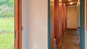 Een hal met houten deuren en een betegelde vloer, die leidt naar een kamer met een witte deur.