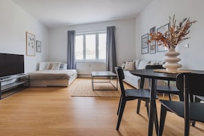 A modern living room with a sofa, a dining table with chairs, a TV, and artwork on the walls. - Deluxe Apartment in the Heart of Bratislava (Bratislava)