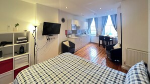 A modern hotel room with a large bed, a flat-screen TV mounted on the wall, a kitchenette, and a dining area with a view of the city. - Quiet and Modern Studio 201 in Nottingham City Centre- Near Victoria (Nottingham)