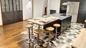 Una cocina moderna con una isla central, taburetes de bar y una mesa de comedor preparada para cuatro.