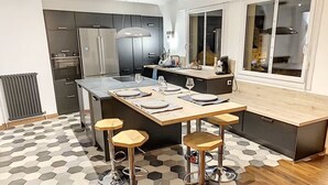 Una cocina moderna con una isla central, taburetes de bar y un ventanal grande.